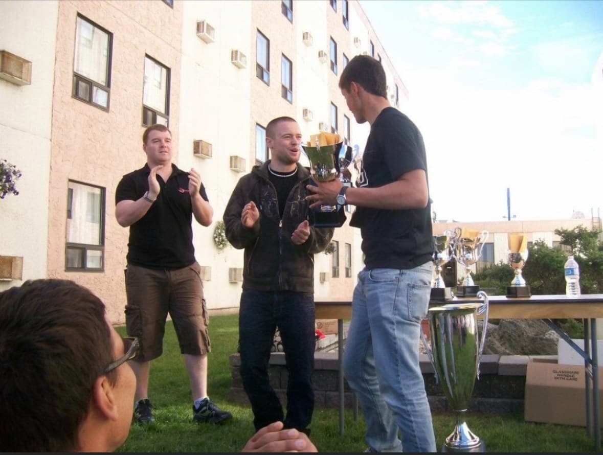 Nik receiving a trophy at an outdoor awards ceremony early in his career.
